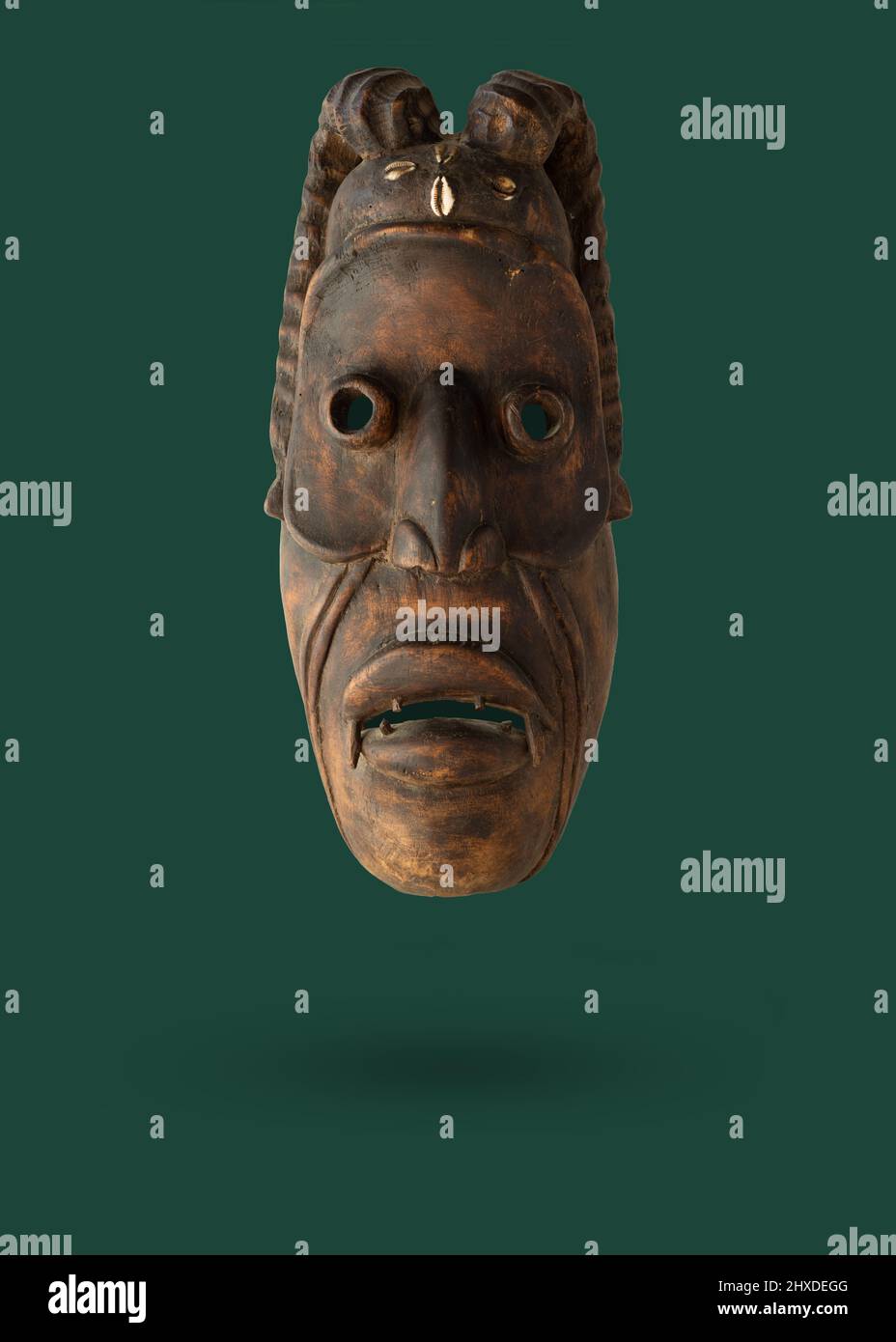 Maschera africana in legno che si levitating su uno sfondo verde. Foto Stock