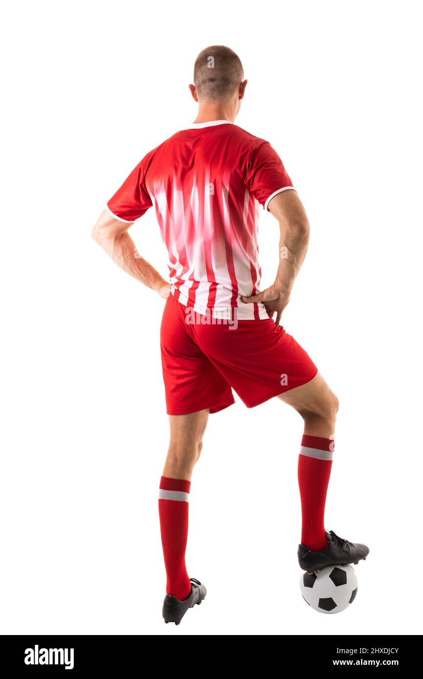 Vista posteriore a tutta lunghezza del giovane atleta caucasico maschio che salpano sulla palla di calcio su sfondo bianco Foto Stock