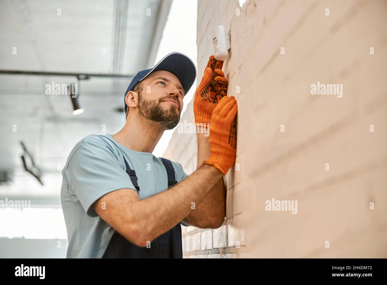 Uomo bearded che controlla la telecamera di sicurezza sulla parete Foto Stock