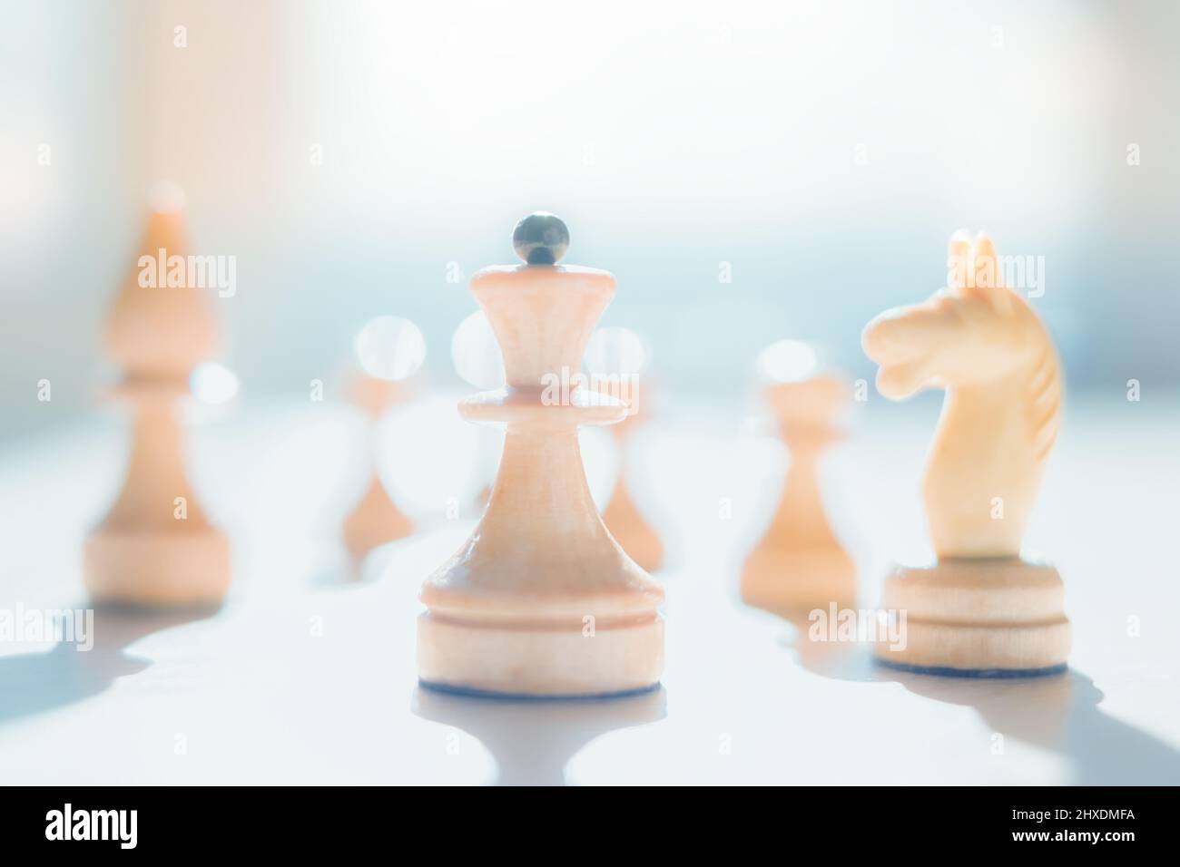 Silhouette di scacchi pezzi bagnati dalla luce del sole. L'immagine è in un tasto alto. La regina degli scacchi guida i guerrieri. Astrazione della strategia di battaglia. BU Foto Stock