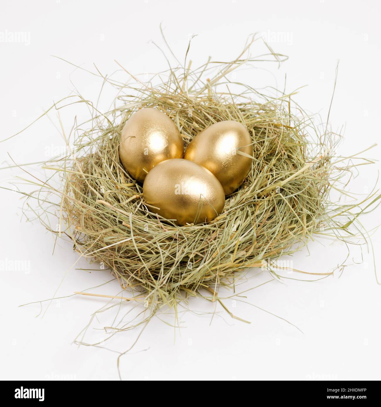 Assicurati di risparmiare oggi per un nido d'uovo d'oro. Scatto di studio di una frizione di uova d'oro che posano in un nido. Foto Stock