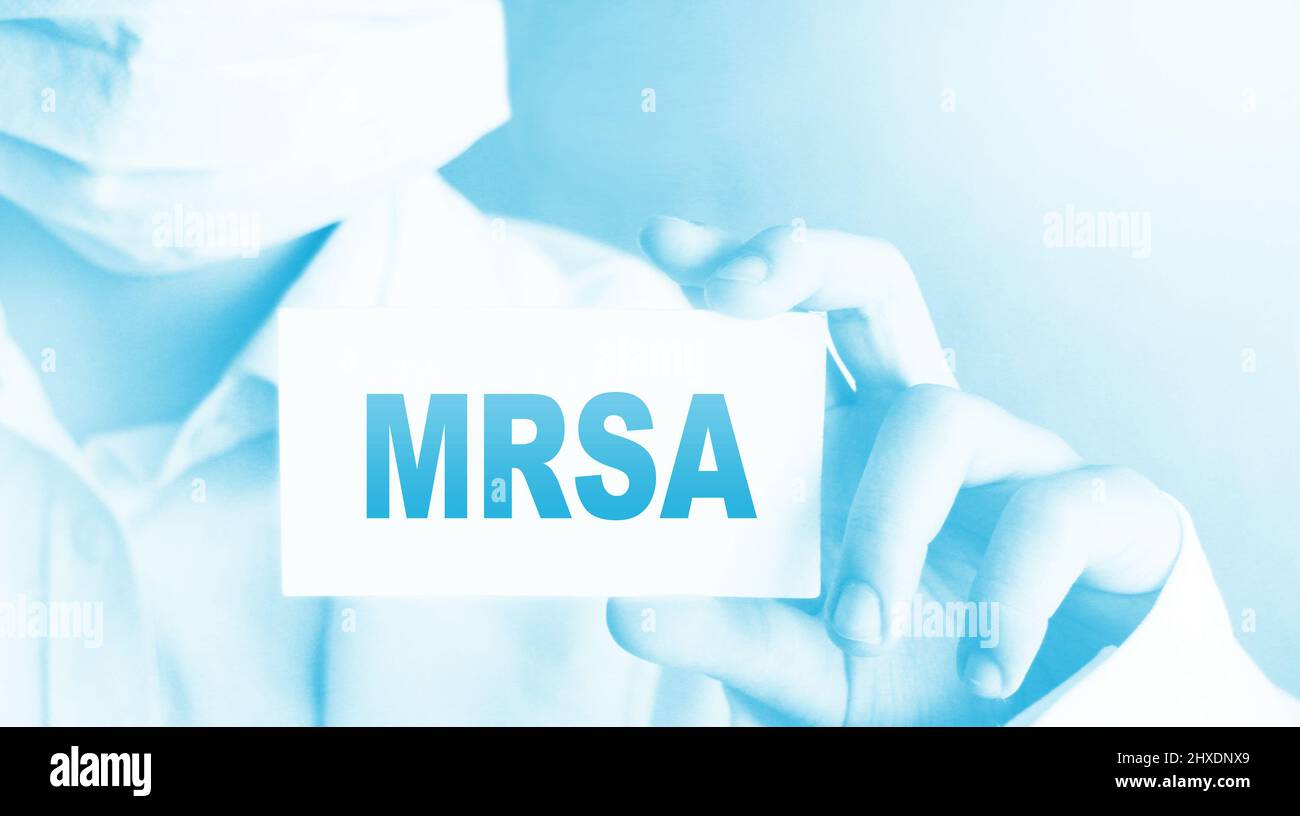 Medico, indossare maschera di protezione del viso mostra una scheda con il testo MRSA. Concetto medico. Foto Stock