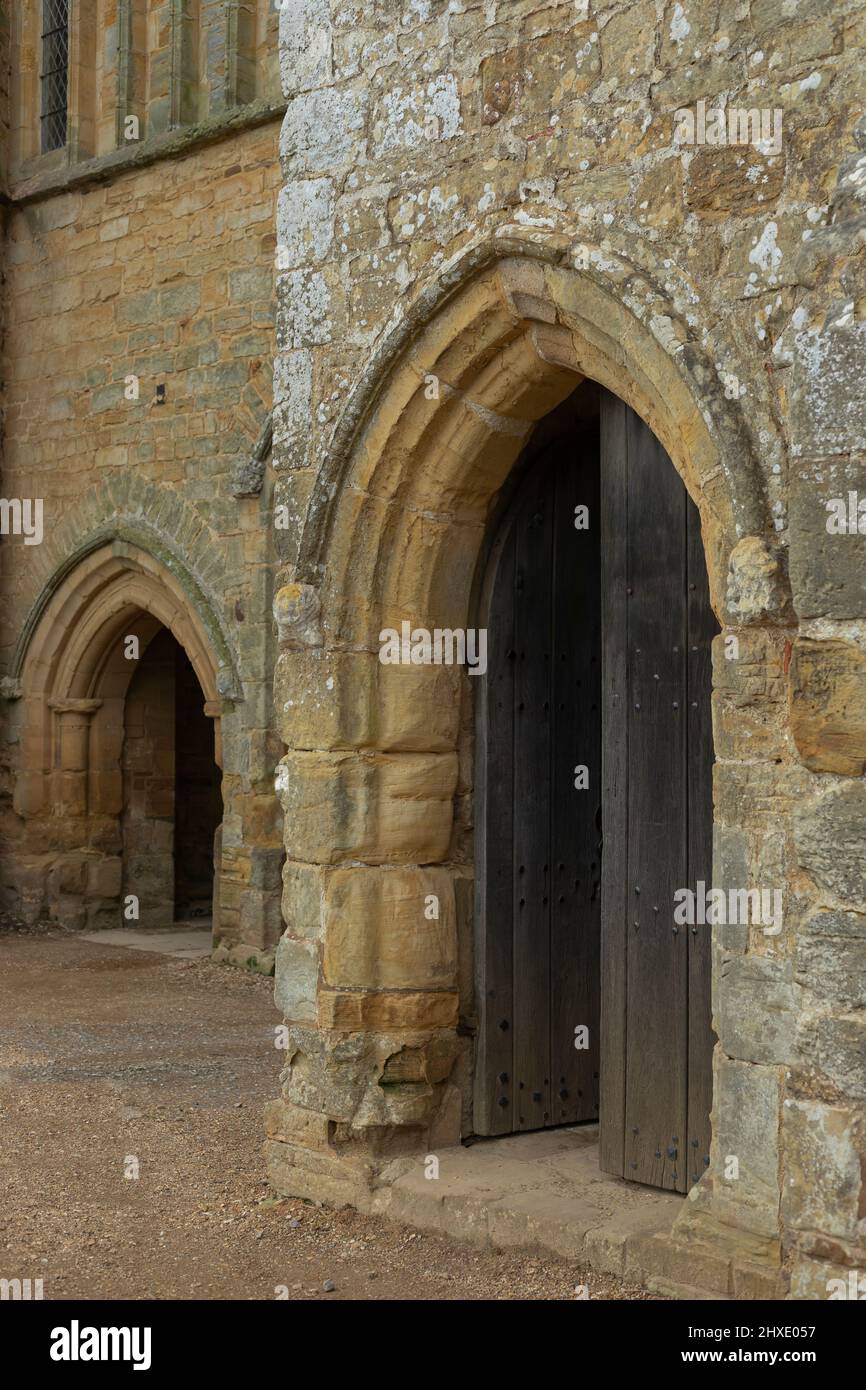 due antiche arcate in pietra con una porta in legno nero nel più grande dei due Foto Stock