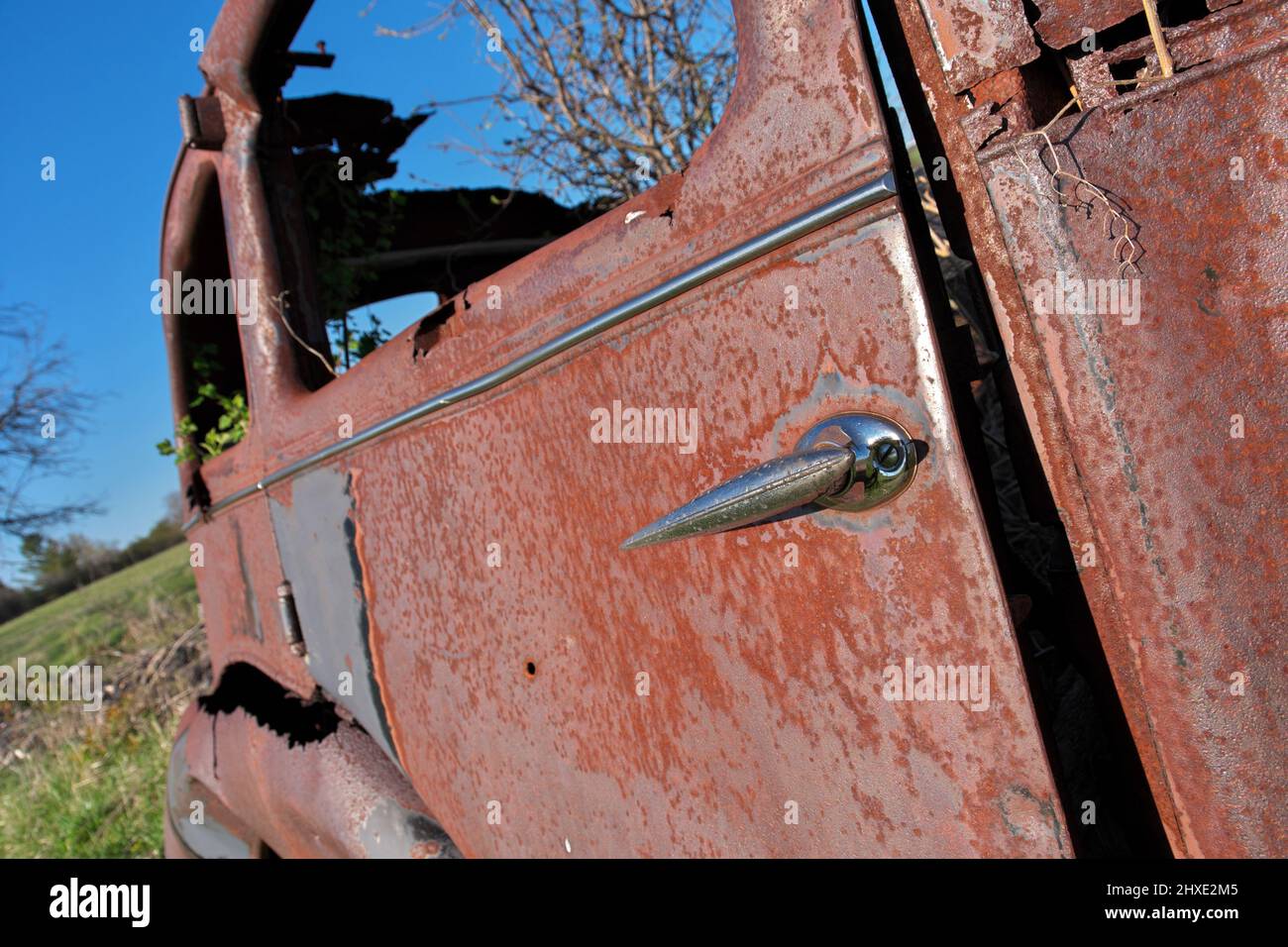 Primo piano di Door of Derelict e arrugginita auto d'epoca in un campo di fattoria in un giorno di sole Foto Stock