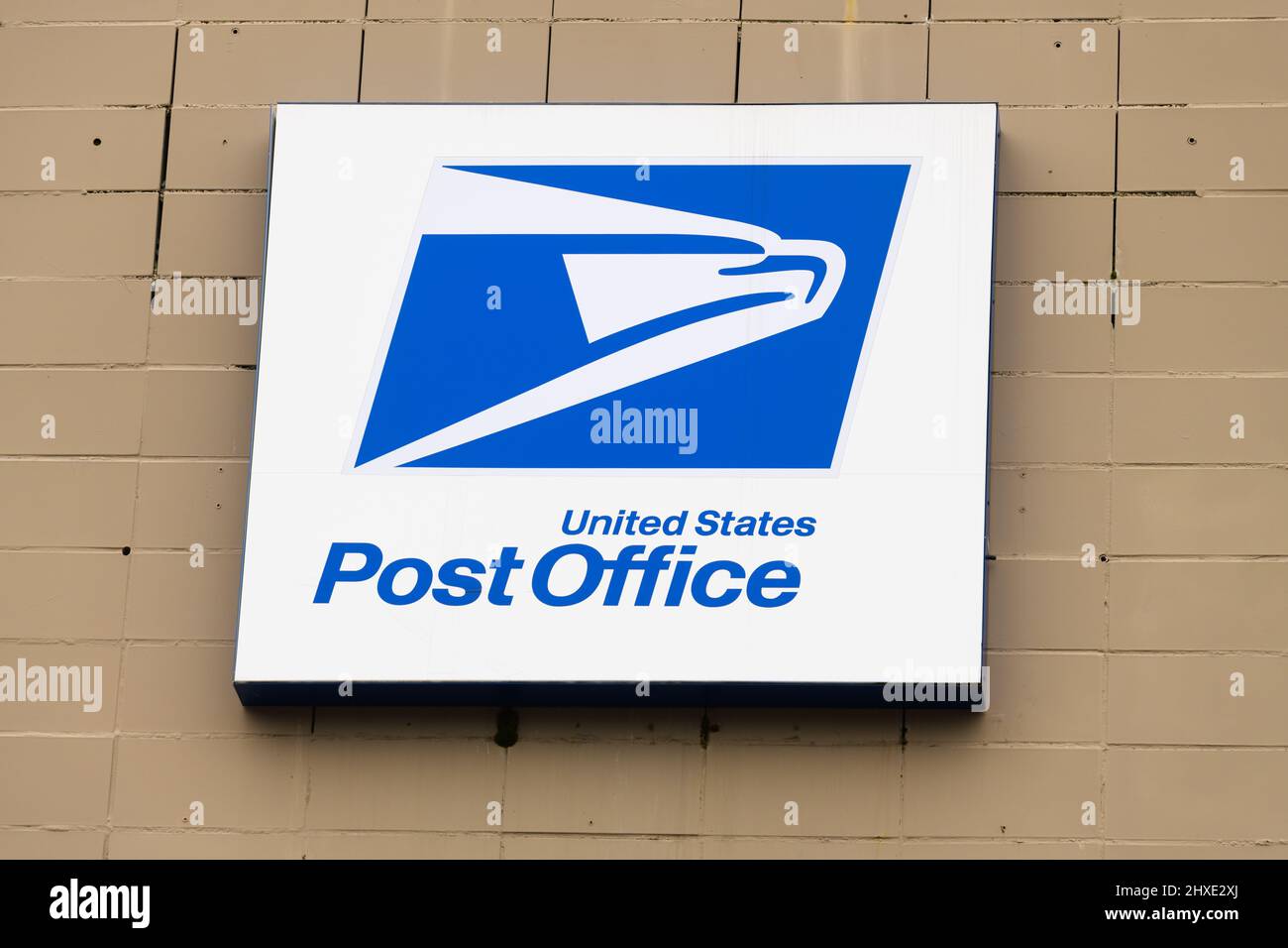 Bellevue, WA, USA - 06 marzo 2022; il cartello dell'ufficio postale degli Stati Uniti, di forma quadrata, blu e bianca, è appeso su una parete in mattoni dipinti Foto Stock