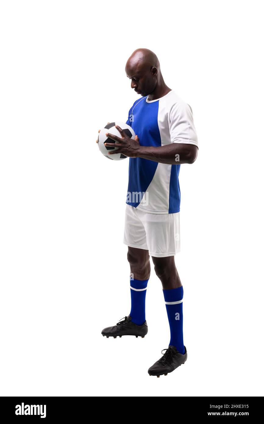 L'intera lunghezza del giovane giocatore di calcio africano americano maschile che tiene la palla su sfondo bianco. Inalterato, sport, competizione e concetto di gioco. Foto Stock