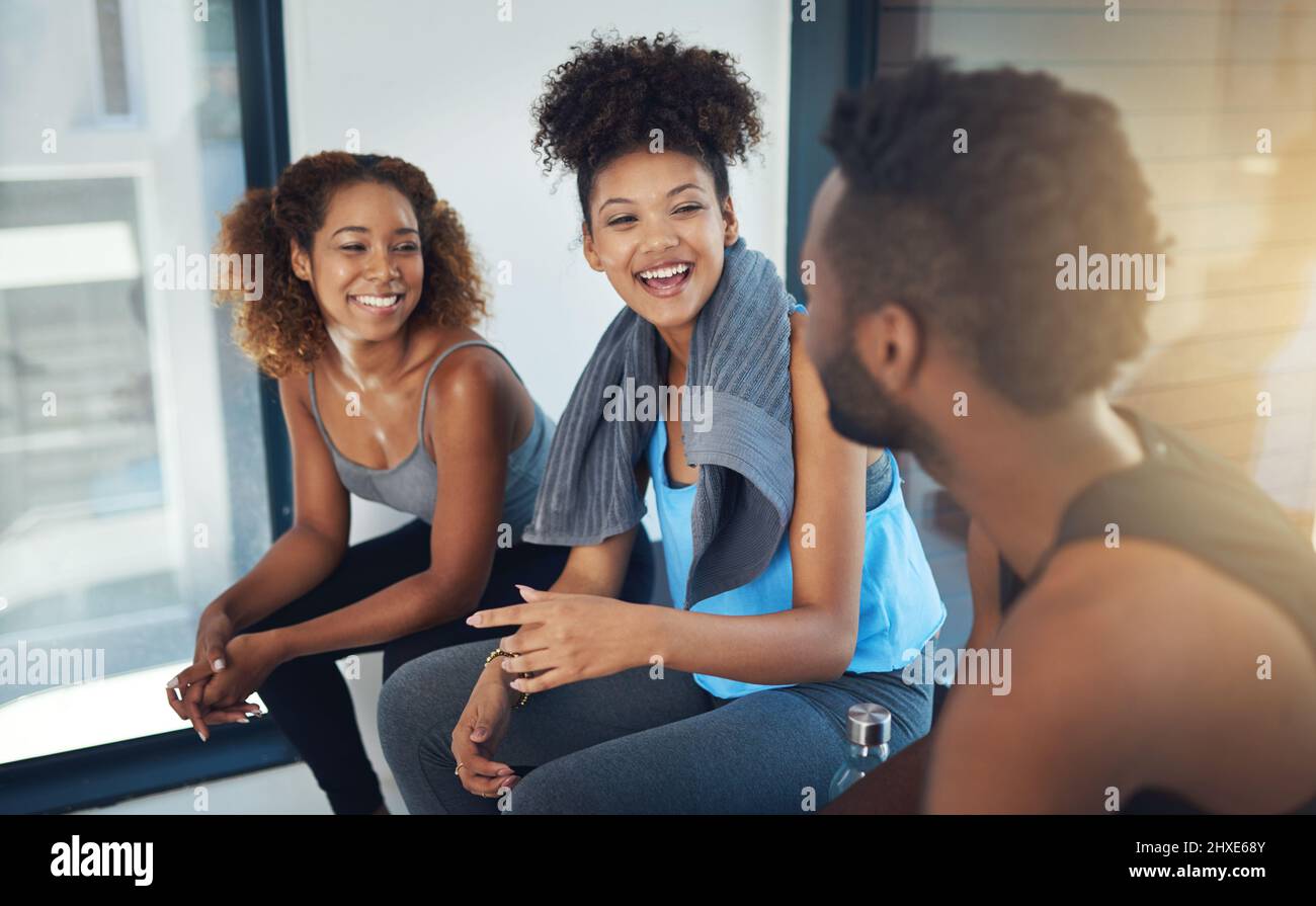 Lasciate che l'energia del gruppo sia il vostro carburante. Scatto corto di tre giovani seduti in palestra dopo la lezione di yoga. Foto Stock