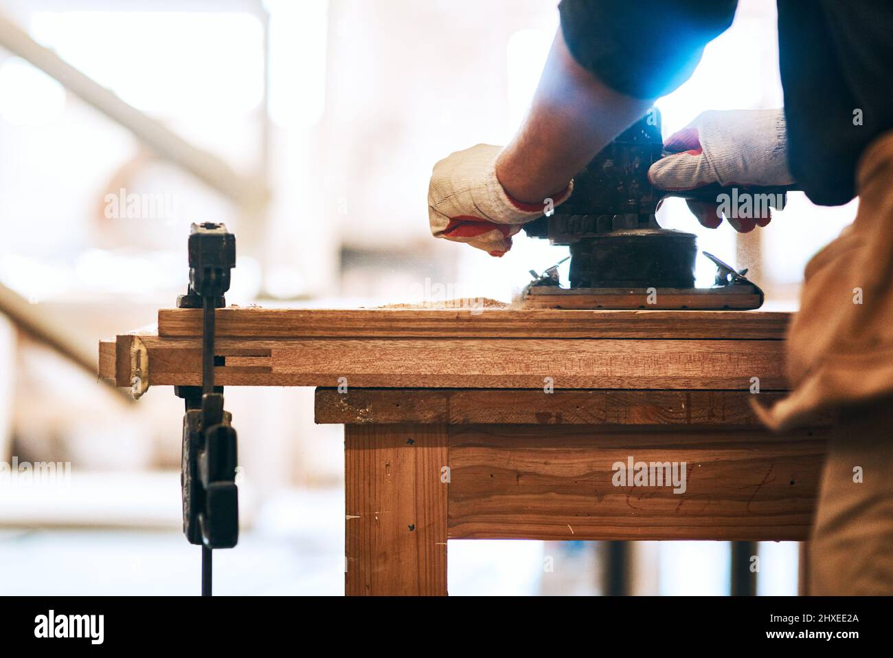 Levigarla alla perfezione. Scatto ritagliato di un legno di levigatura da carpentiere irriconoscibile con una levigatrice per palme all'interno di un'officina. Foto Stock