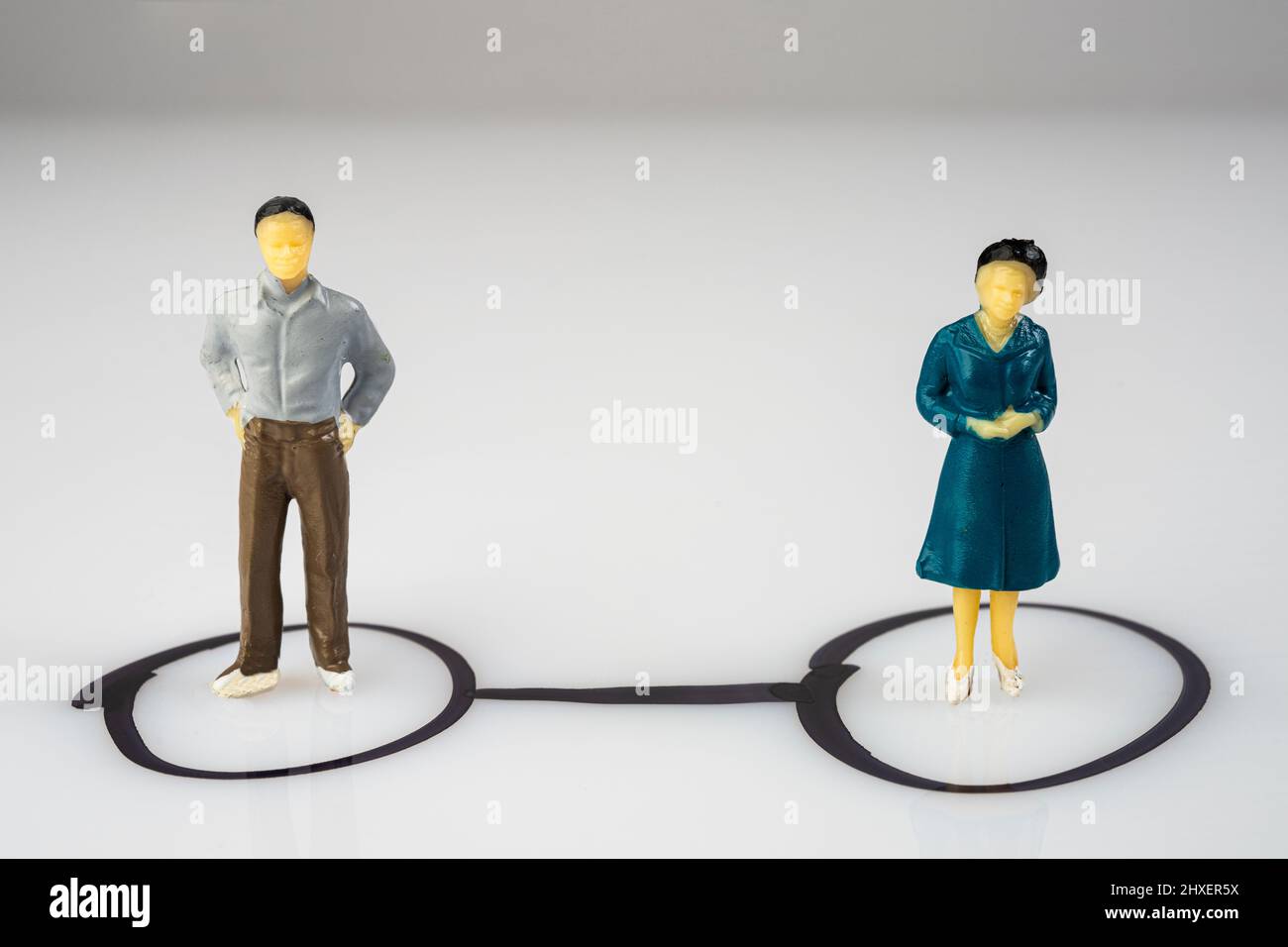 la relazione tra due modelli miniaturizzati isolati all'interno di un cerchio disegnato su una superficie Foto Stock