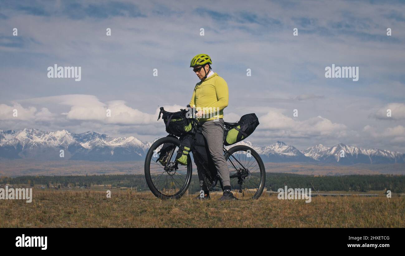 L'uomo viaggia in bicicletta su terreni misti con bikepacking. Il viaggio  del viaggiatore con le borse della bicicletta. Sport bikepacking, bici,  abbigliamento sportivo in verde b Foto stock - Alamy