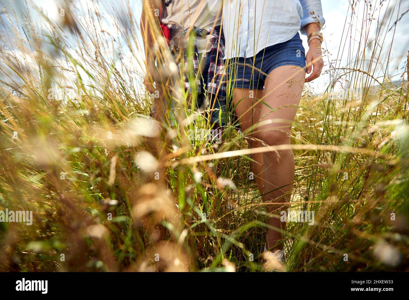 Primo piano di coppia escursioni in campo, attraverso l'erba. Natura all'aperto. Coppia caucasica. Sport, libertà, concetto di vacanza. Foto Stock