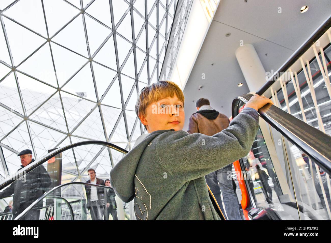 Bambino su scala mobile sembra comunque fiduciosi e sorrisi Foto Stock