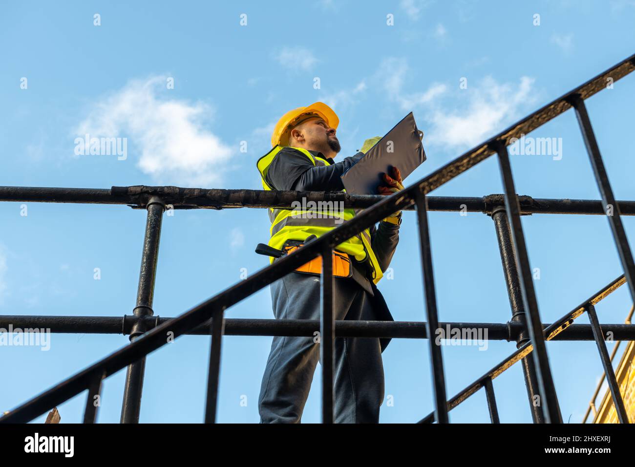 Un caposquadra di edifici che prende appunti e ispeziona i lavori di costruzione in cantiere. Foto Stock