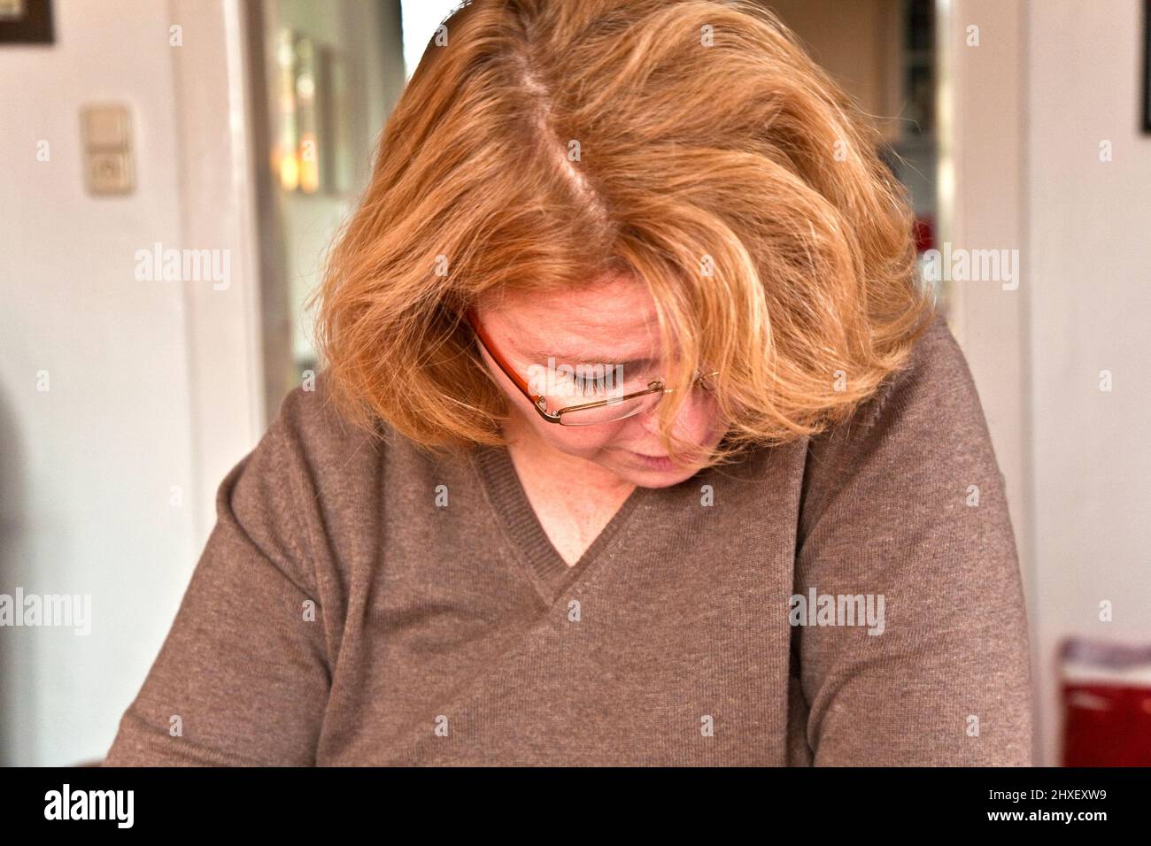 Donna con i capelli rossi sta leggendo il giornale Foto Stock