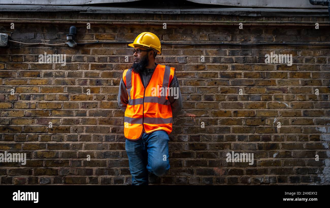 Ritratto di un lavoratore di costruzione asiatico che indossa elmetto e gilet ad alta visibilità. Foto Stock