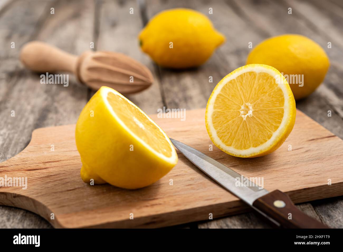 Limone fresco tagliato a metà con coltello su tagliere di legno. Foto Stock