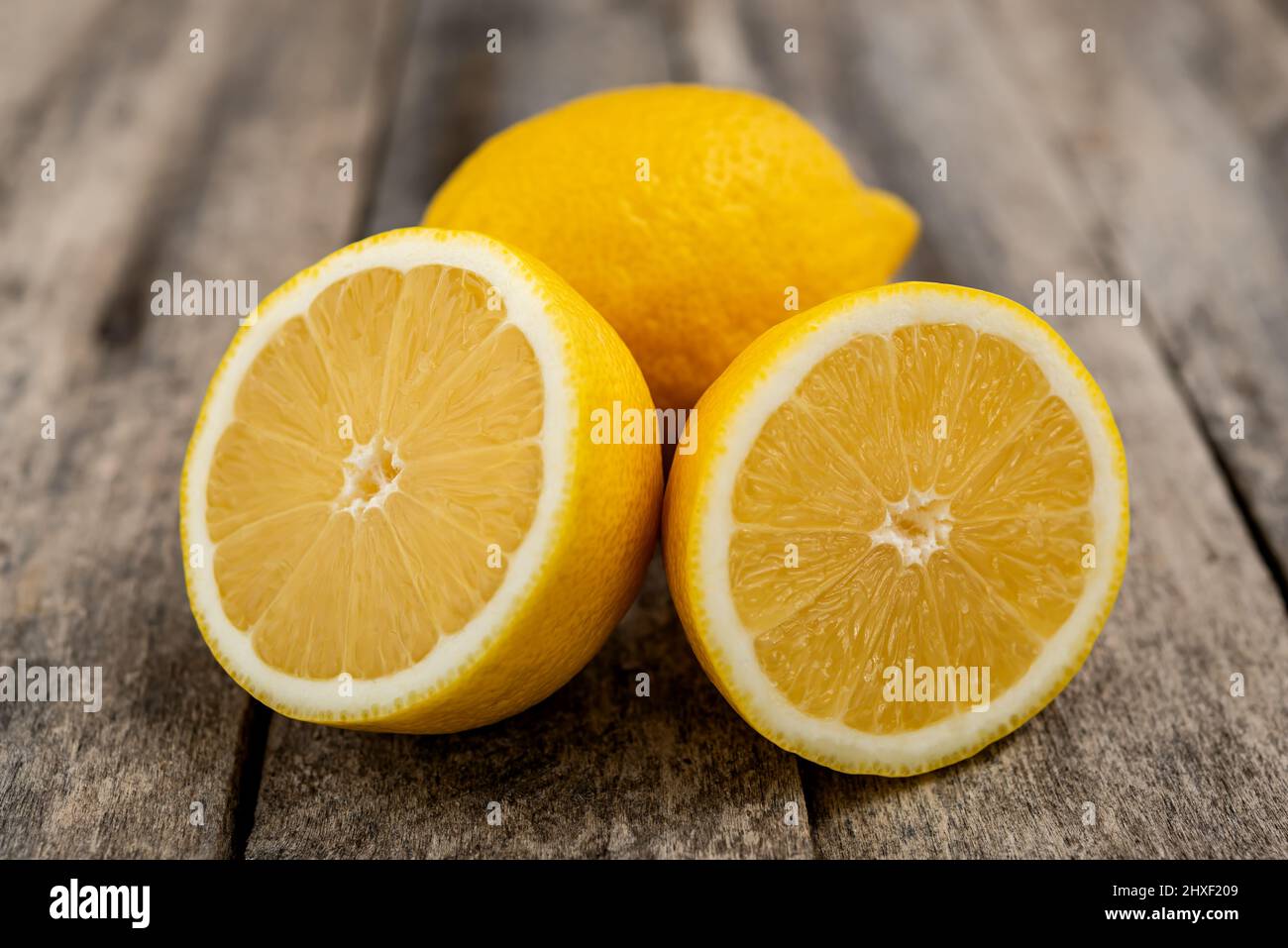 Limone fresco tagliato a metà su tavola rustica in legno. Foto Stock