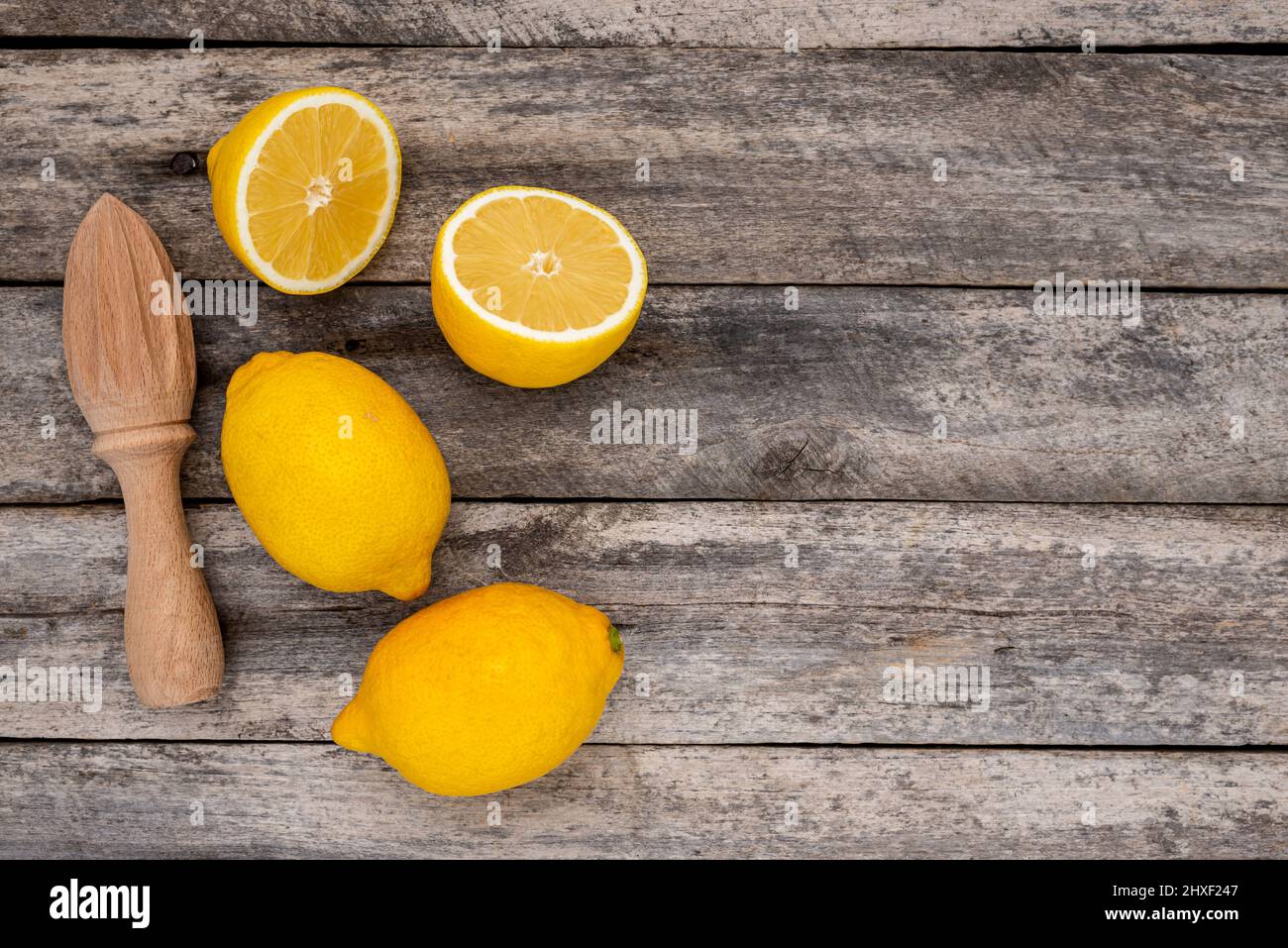 Limoni freschi e spremiagrumi in legno su un tavolo rustico con spazio per la copia del testo. Vista dall'alto. Foto Stock