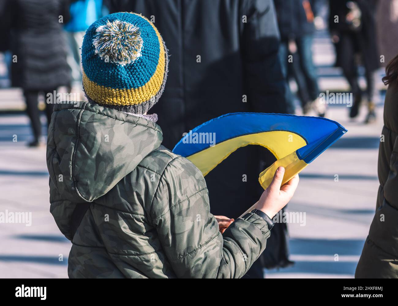 Bambino o ragazzo con abiti invernali, bandiera e cappello ucraino,  rifugiati durante la guerra in Ucraina, causati da Putin e Russia Foto  stock - Alamy
