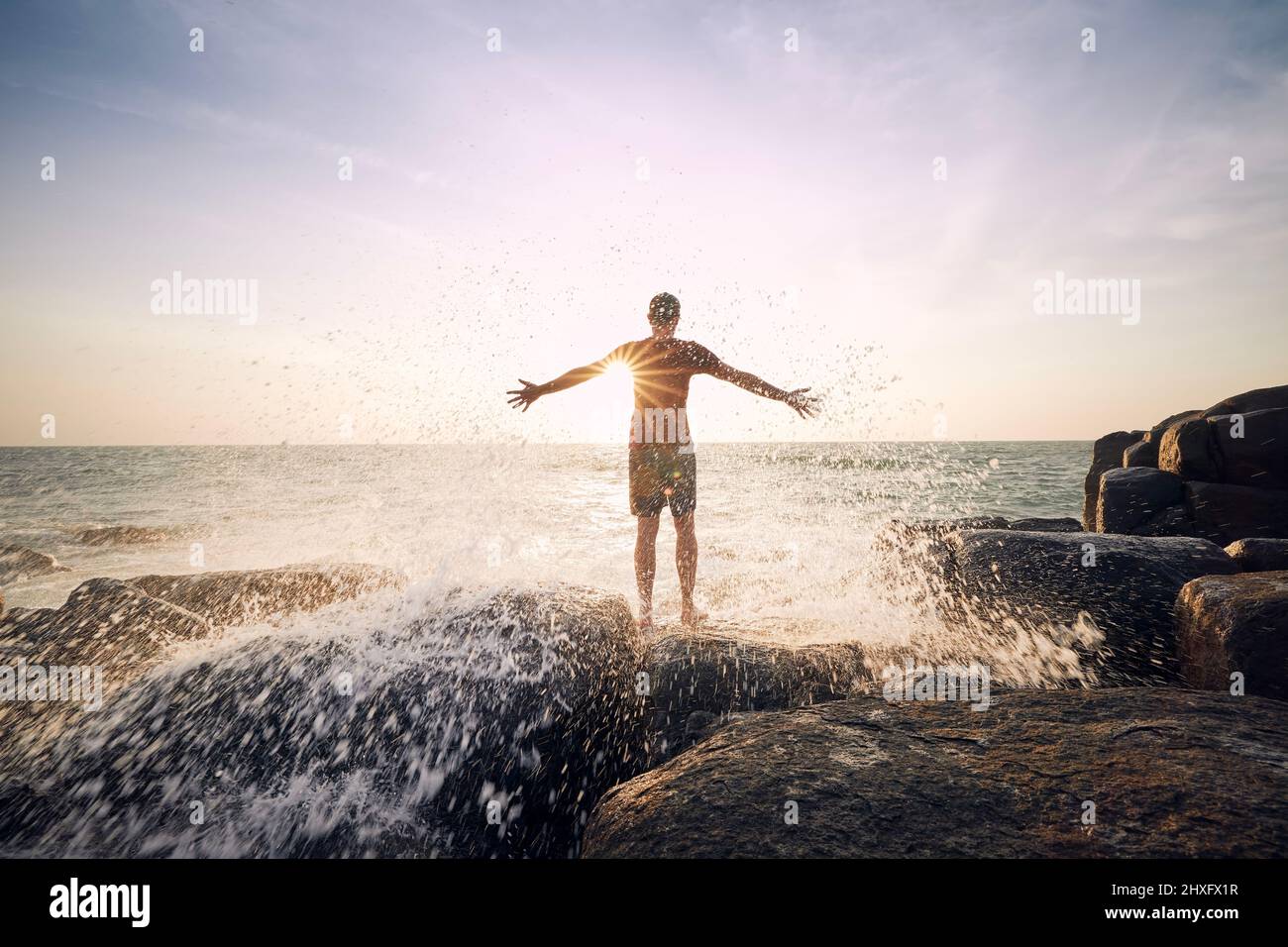 Vista posteriore dell'uomo che gode di spruzzi d'acqua dal mare al bellissimo tramonto in Sri Lanka. Foto Stock