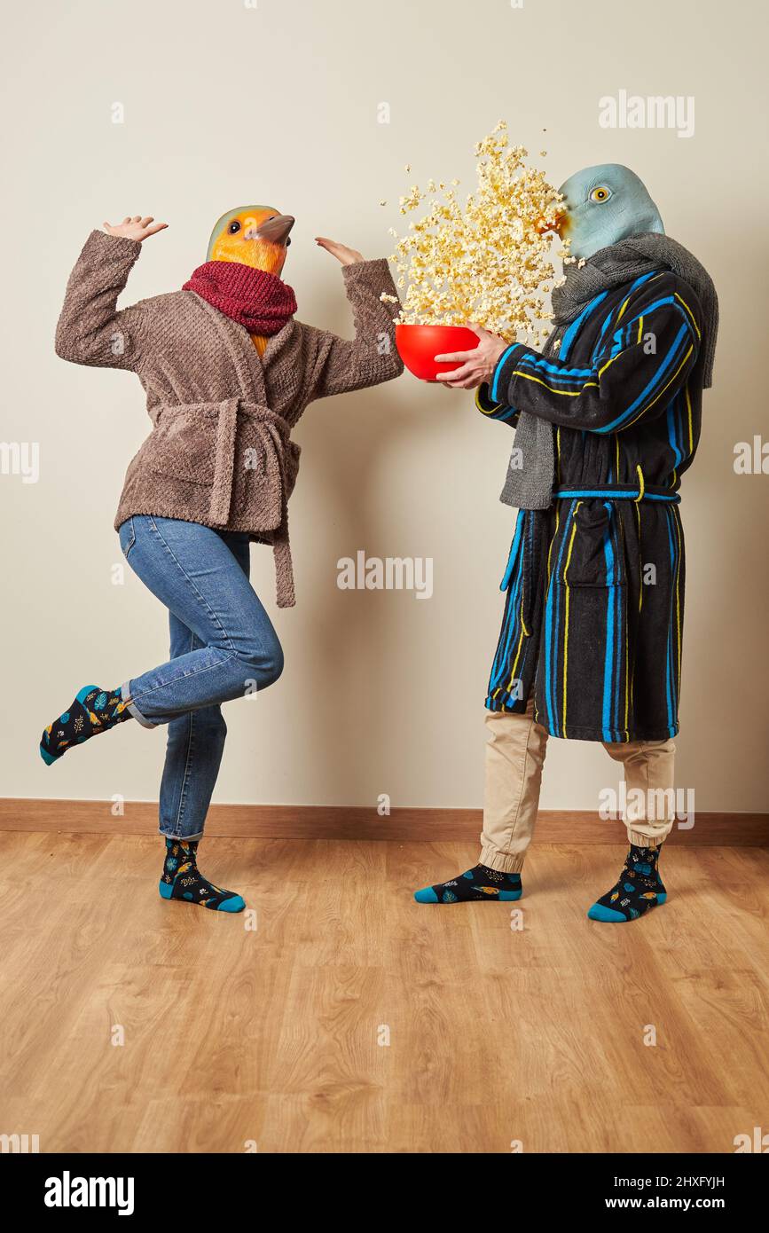 Coppia vestita come uccelli hanno una sorpresa per popcorn in aria Foto Stock