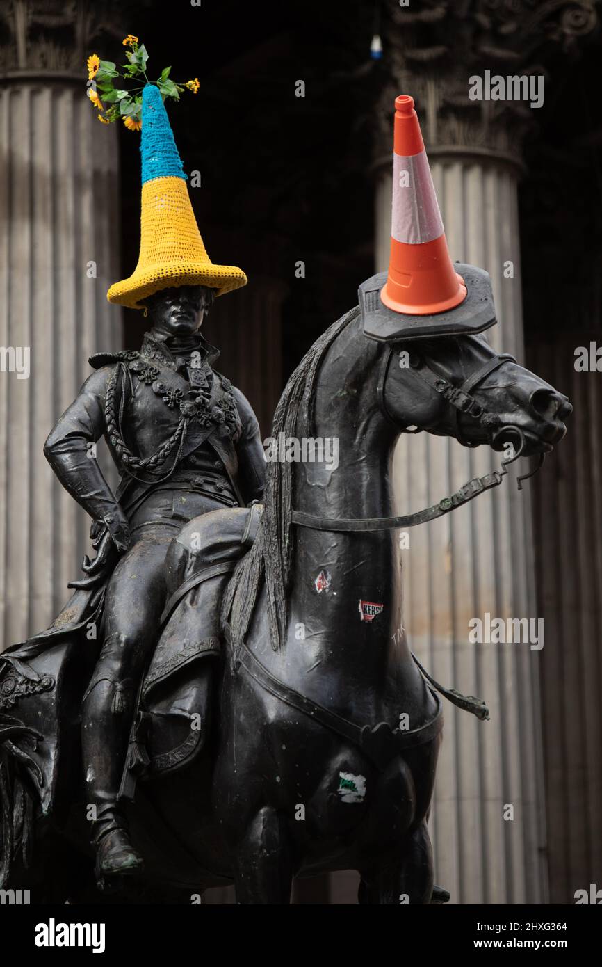 Glasgow, Regno Unito, 12th marzo 2022. Statua del Duca di Wellington in Queen Street con un cappello a cono di polizia a tema bandiera Ucraina blu e giallo, come accovacciato da Pauline McWhirter, a sostegno dell'Ucraina nella loro attuale guerra con il Presidente PutinÕs Russia, a Glasgow, Scozia, 12 marzo 2022. Photo credit: Jeremy Sutton-Hibbert/Alamy Live News. Foto Stock