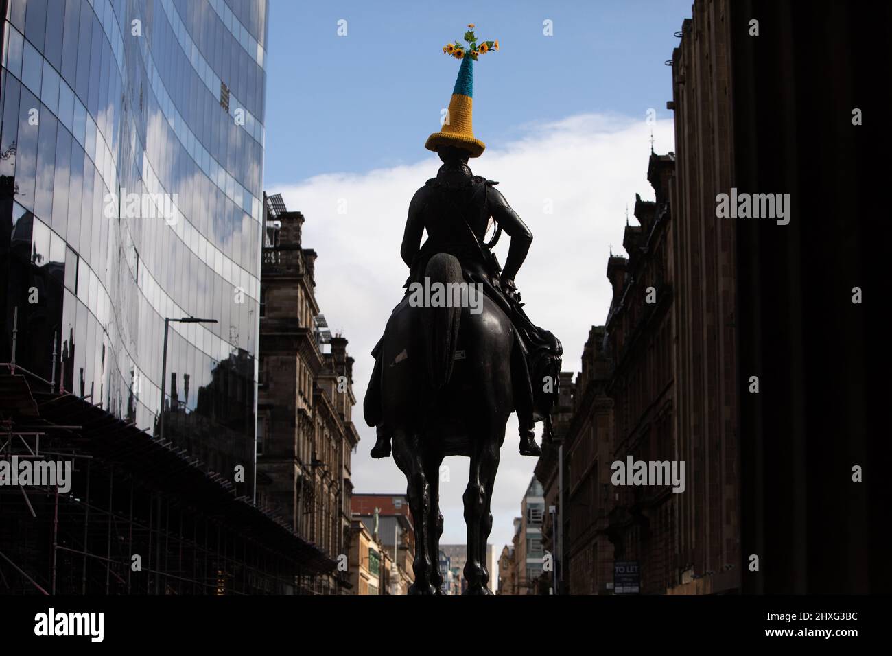 Glasgow, Regno Unito, 12th marzo 2022. Statua del Duca di Wellington in Queen Street con un cappello a cono di polizia a tema bandiera Ucraina blu e giallo, come accovacciato da Pauline McWhirter, a sostegno dell'Ucraina nella loro attuale guerra con il Presidente PutinÕs Russia, a Glasgow, Scozia, 12 marzo 2022. Photo credit: Jeremy Sutton-Hibbert/Alamy Live News. Foto Stock