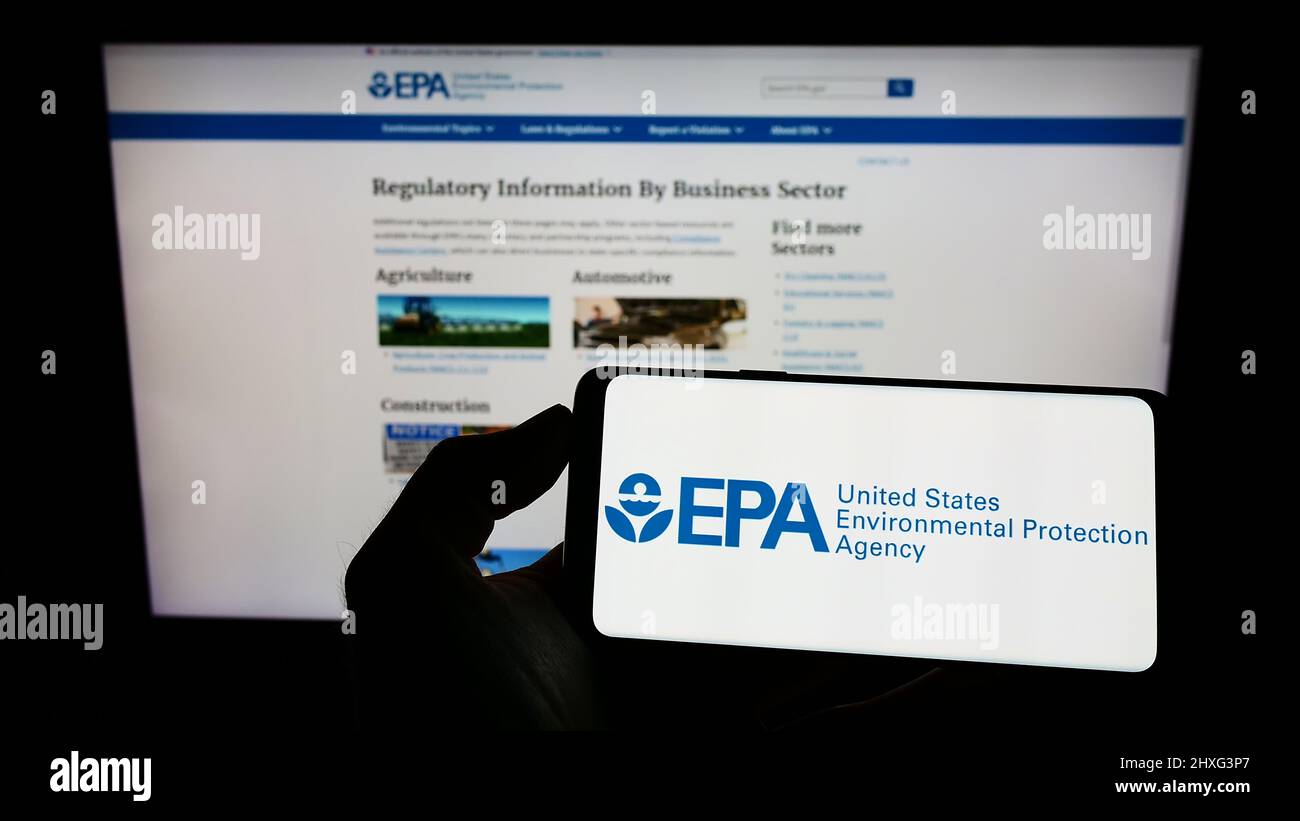 Persona che tiene il cellulare con il logo della US Environmental Protection Agency (EPA) sullo schermo di fronte alla pagina web. Mettere a fuoco sul display del telefono. Foto Stock
