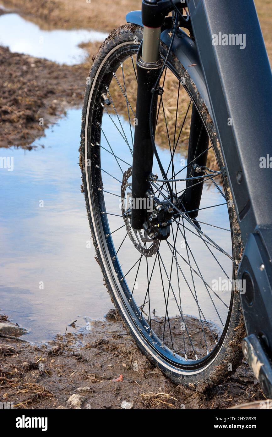 Con la bicicletta da trekking sulle fangose stradine di campagna. Pneumatici per biciclette con freni a disco su strada fangosa e umida. Foto Stock