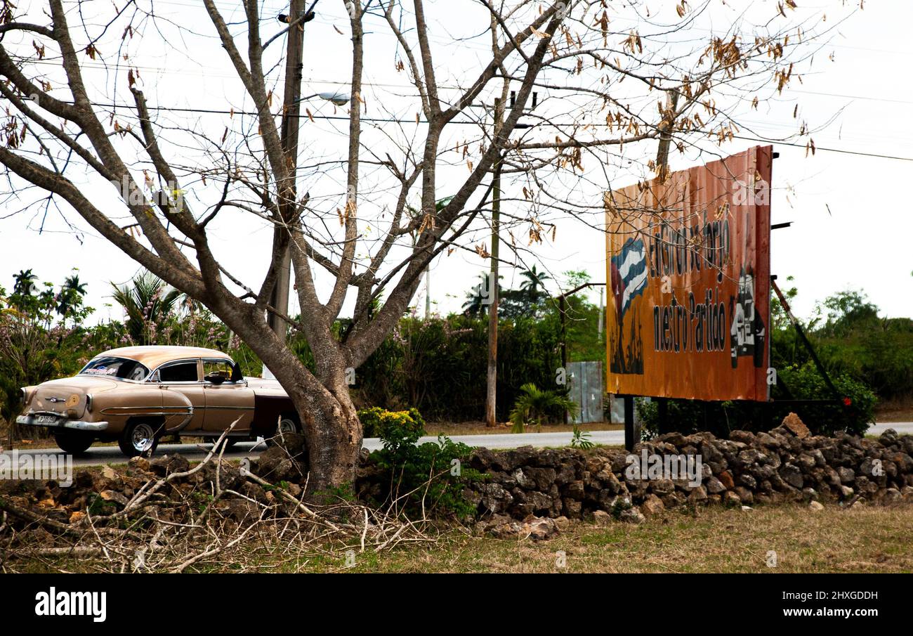 Auto cubana classica su una strada a Giron, Cuba vicino l'Avana; un cartellone sul lato della strada vicino l'Avana, Cuba. Foto Stock