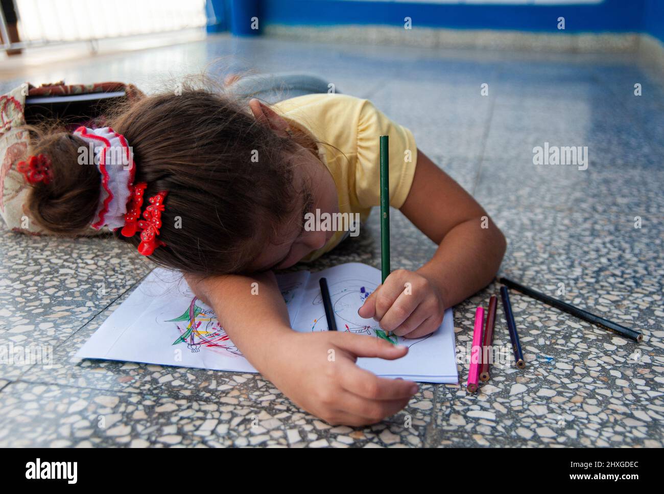 La giovane bambina cubana depone un pavimento dipinto alcune opere d'arte in un edificio a l'Avana, Cuba. Foto Stock