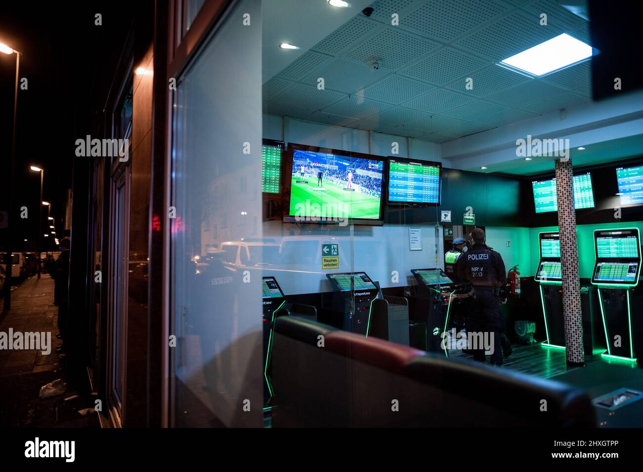 Duisburg, Germania. 12th Mar 2022. Gli agenti di polizia camminano attraverso i locali di un negozio di scommesse. La polizia ha razziato un ufficio scommesse nel nord di Duisburg. Il Ministro degli interni del Nord Reno-Westfalia Reul (CDU), è sul posto per ottenere un quadro della situazione. Credit: Fabian Strauch/dpa/Alamy Live News Foto Stock