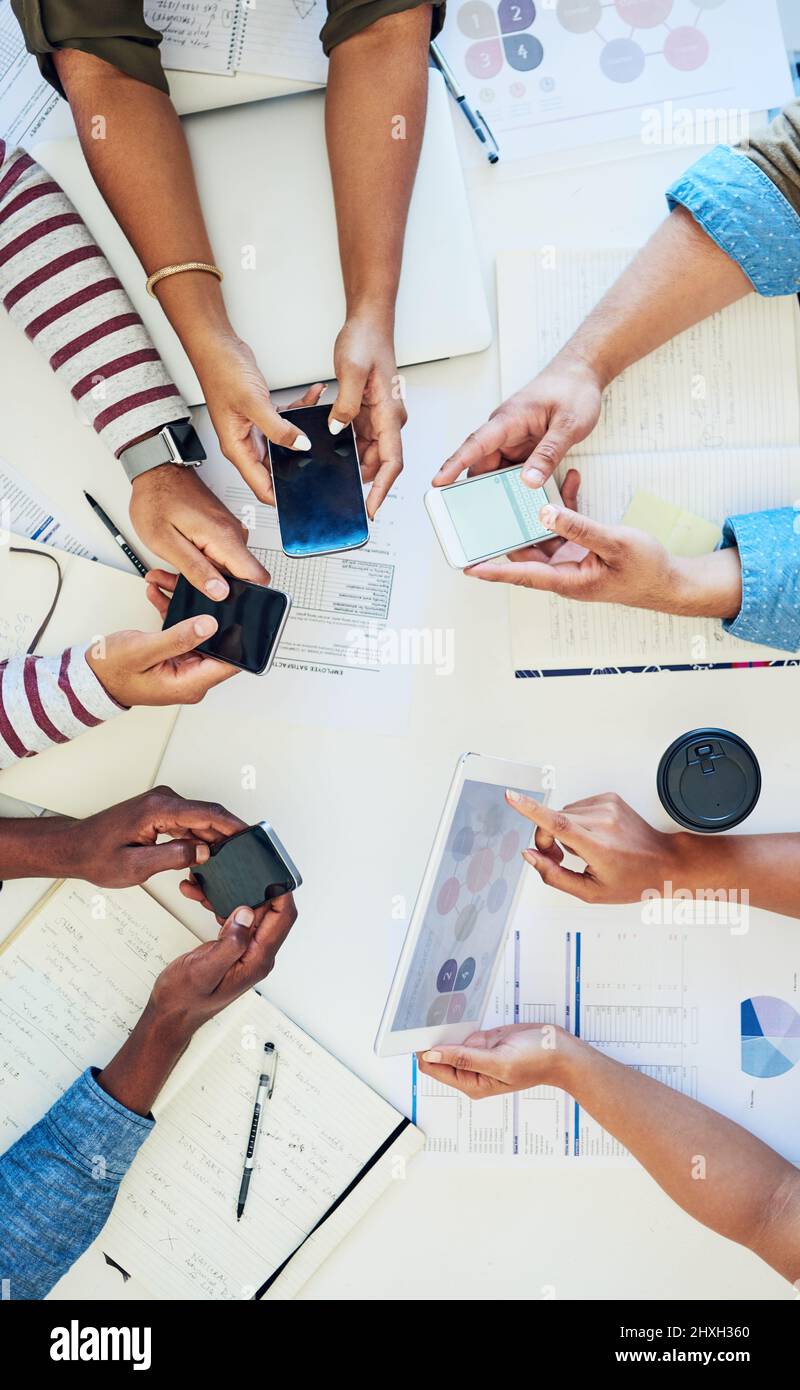 Strumenti essenziali per una collaborazione efficace. Scatto ritagliato di un gruppo di colleghi che utilizzano dispositivi intelligenti durante una riunione al lavoro. Foto Stock