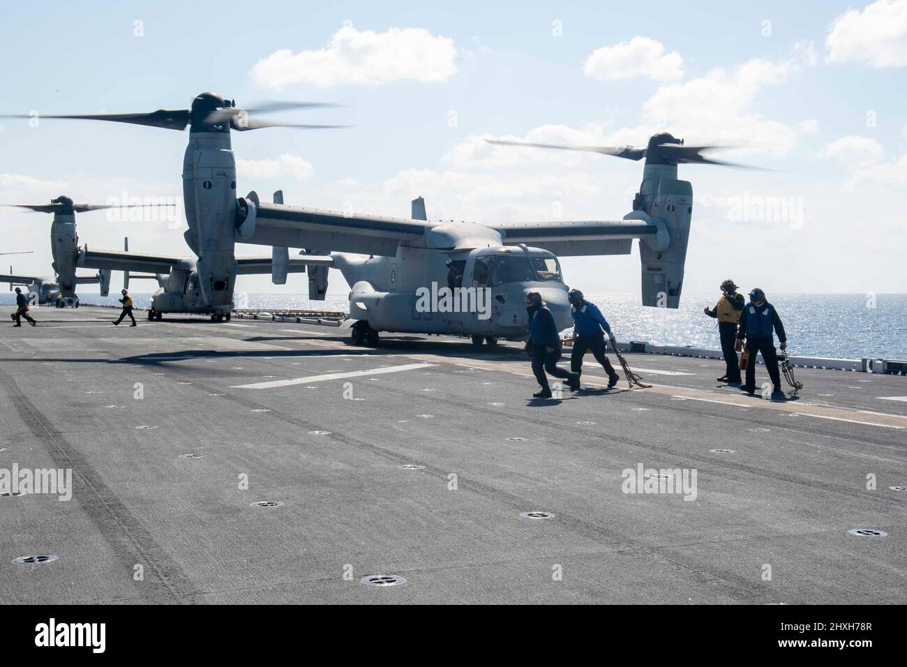 PACIFIC OCEAN (8 marzo 2022) i marinai assegnati alla nave d'assalto anfibio dispiegata in avanti USS America (LHA 6) rimuovono i cunei e le catene da un aereo tiltrotor MV-22B Osprey dalla Marine Expeditionary Unit (MEU) del 31st. L'America, nave principale dell'America Amphibious Ready Group, insieme al MEU 31st, opera nell'area di responsabilità della flotta USA 7th per migliorare l'interoperabilità con alleati e partner e servire come forza di risposta pronta a difendere la pace e la stabilità nella regione Indo-Pacific. (STATI UNITI Foto della Marina di Seaman Matthew Bakerian, specialista della comunicazione di massa) Foto Stock