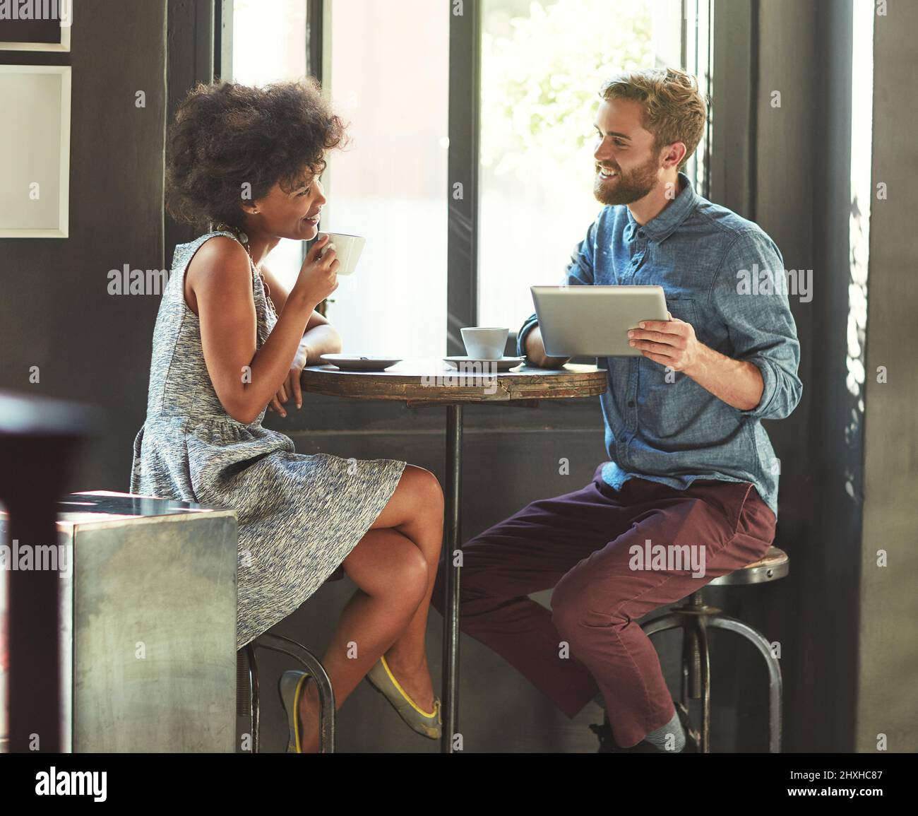 Quella prima data. Scatto di una giovane coppia utilizzando un tablet digitale insieme in una data caffè. Foto Stock
