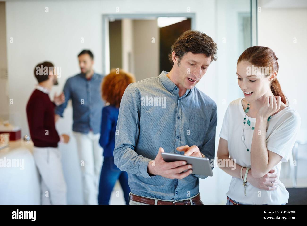 Basta guardare questa pratica funzione. Scatto di un uomo d'affari e del suo collega che guardano il suo tablet insieme in ufficio. Foto Stock