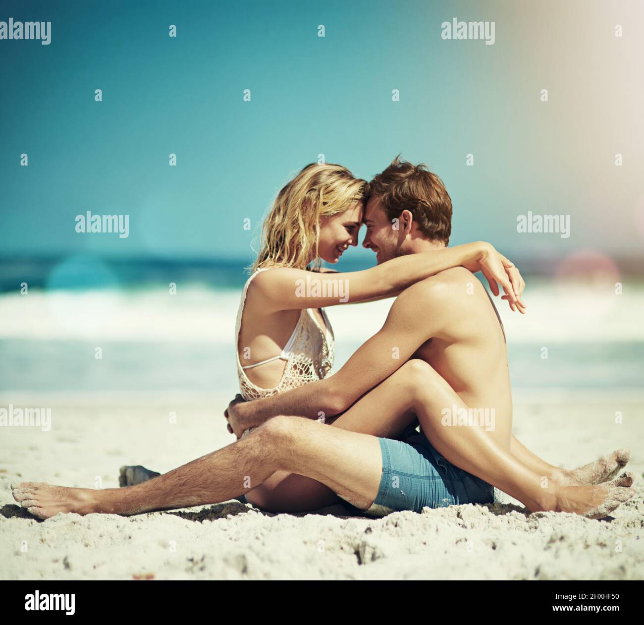 Innamorarsi ancora di più. Scatto completo di una giovane coppia affettuosa seduta faccia a faccia sulla spiaggia. Foto Stock