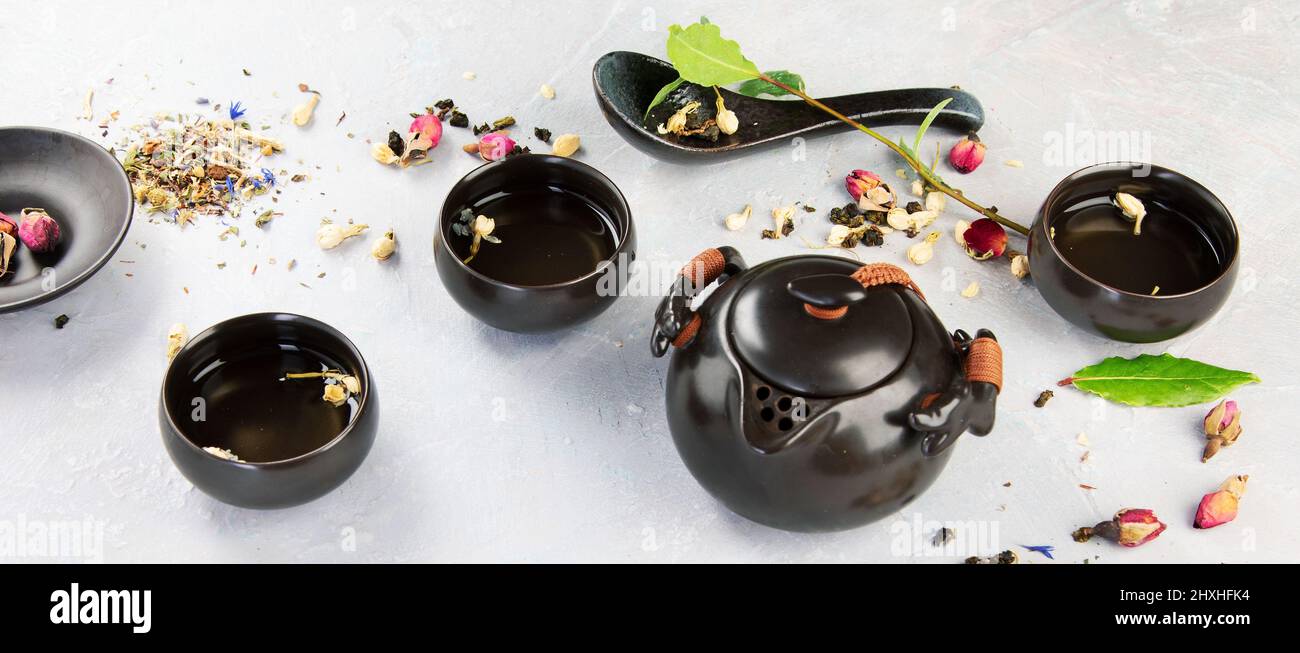 Tè asiatico su sfondo chiaro. Foglie di piante, composizione di tisane naturali. Panorama Foto Stock