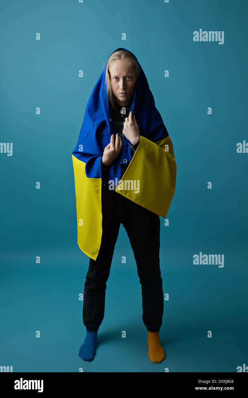 Una vera donna bionda Ucraina durante la guerra con la bandiera Ucraina gialla e blu sulla sua testa. La Russia ha attaccato l'Ucraina il 24 febbraio 2022. Foto Stock
