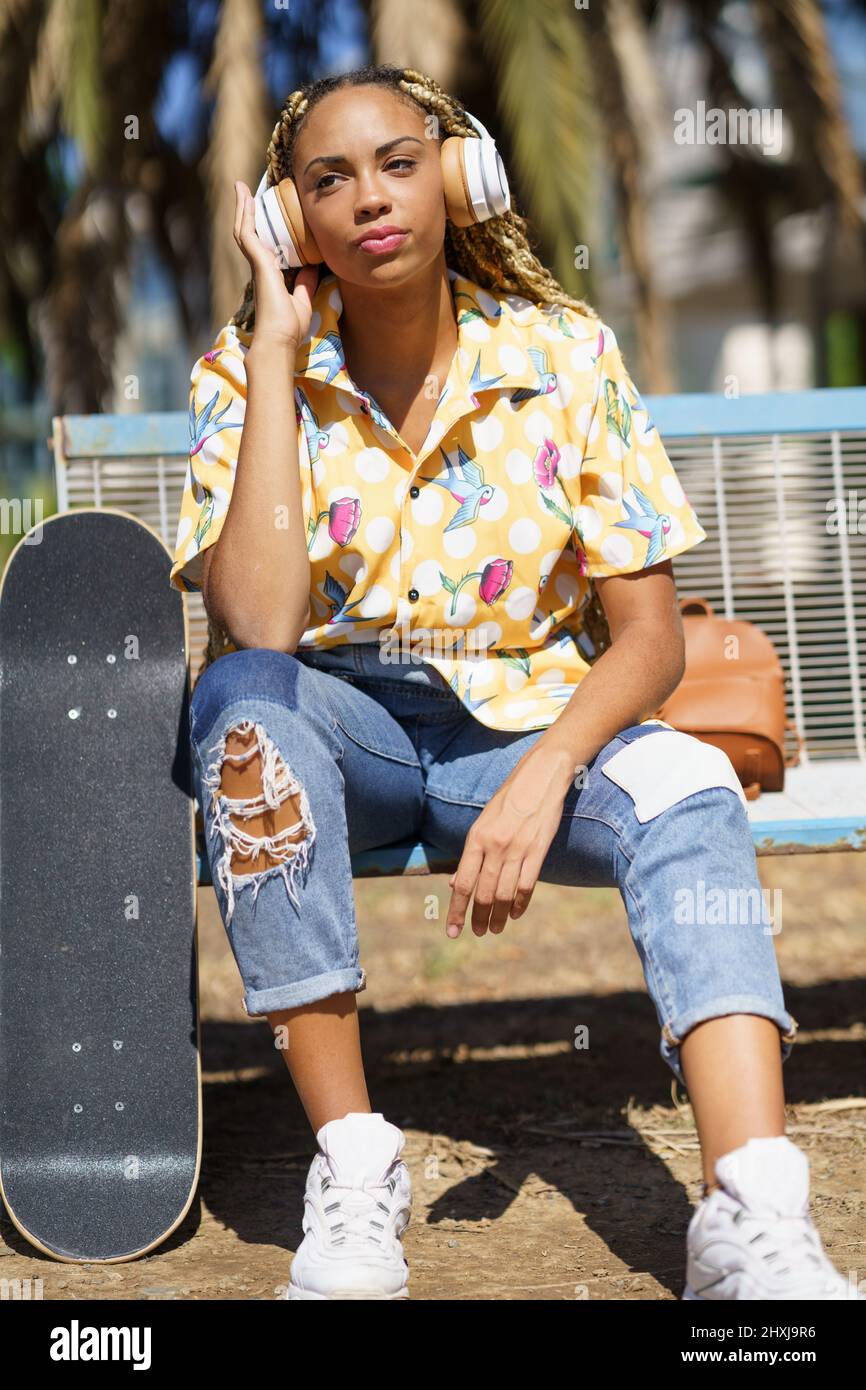 Skater femminile afroamericana che ascolta musica Foto Stock