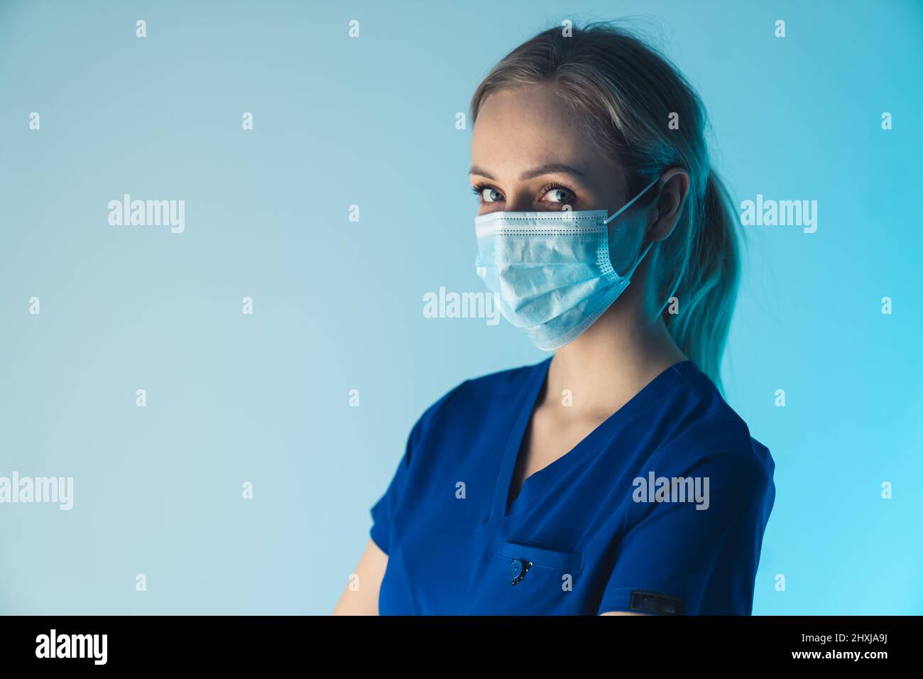 Serio operatore sanitario donna guardando la macchina fotografica, indossare maschera chirurgica per prevenire la diffusione di batteri e virus. Foto di alta qualità Foto Stock