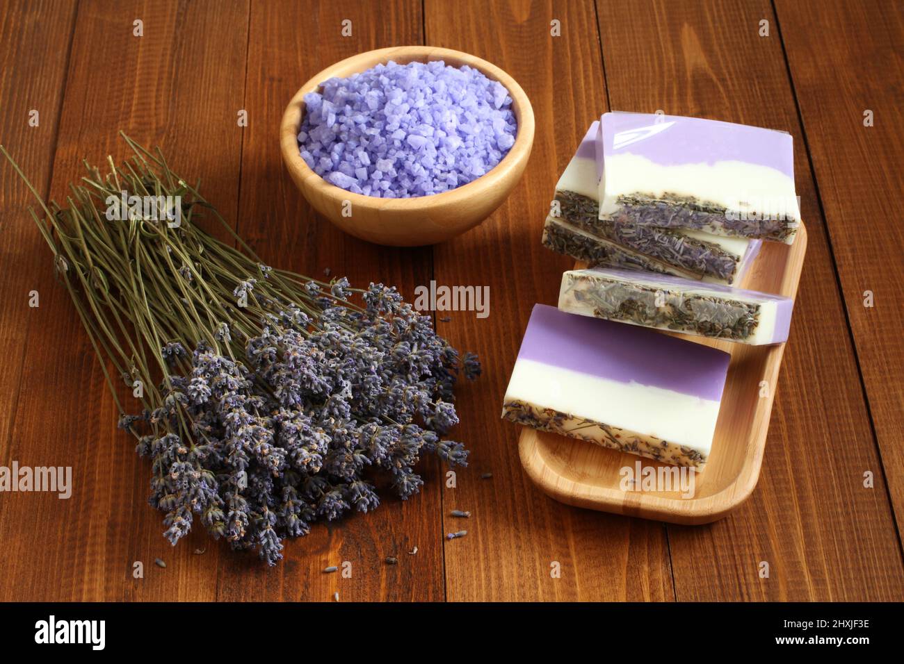 Sale marino con lavanda in una ciotola di bambù, sapone fatto da lavanda, olio d'oliva e burro di cacao su una piastra di bambù e fiori di lavanda essiccati si trovano Foto Stock