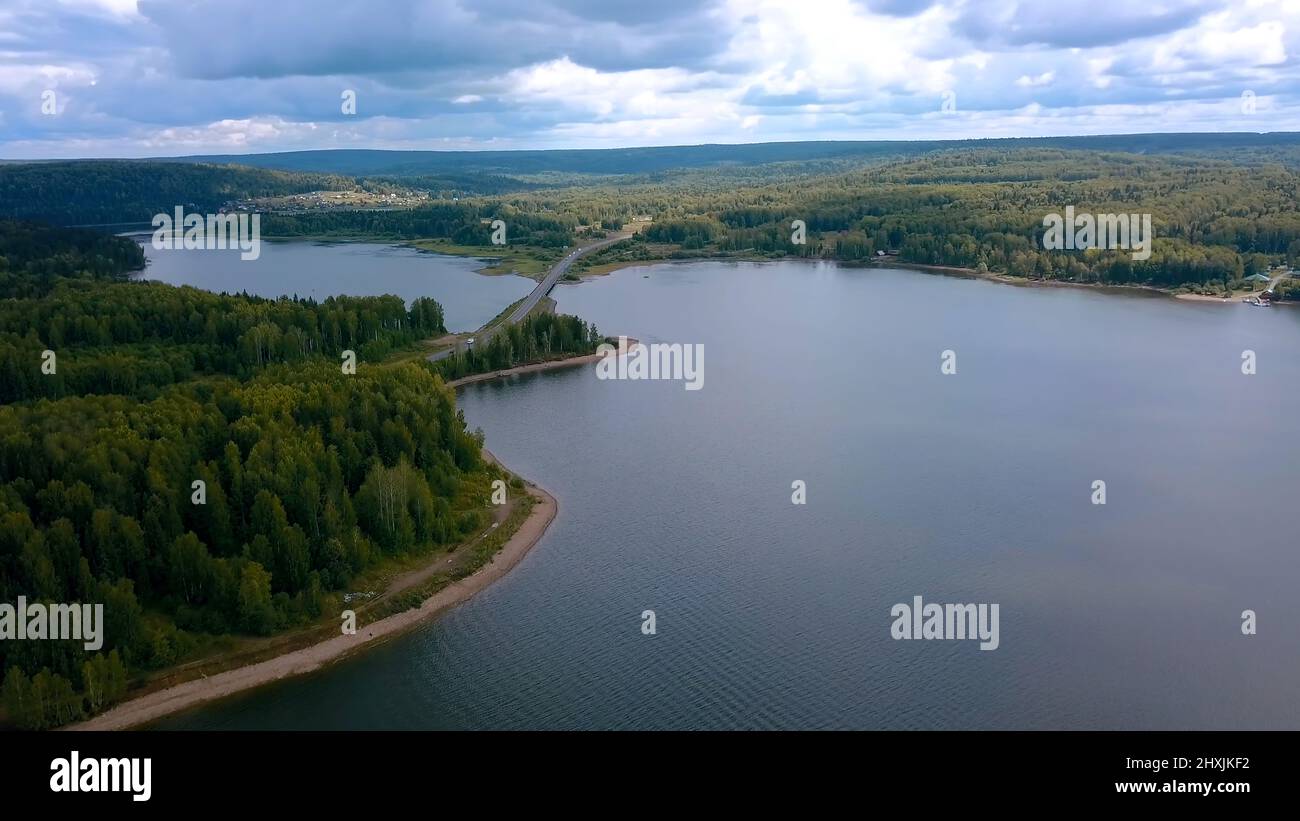 Un enorme ponte sul fiume. Clip. Vista dall'alto. Un enorme ponte su un grande fiume sullo sfondo di un cielo senza nuvole e di un'enorme foresta Foto Stock