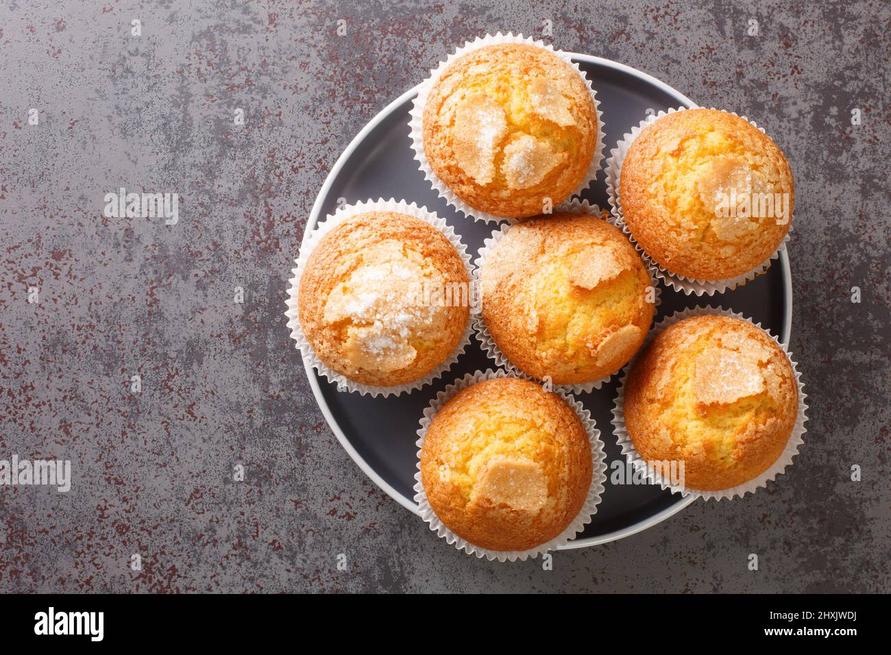 Primo piano di un mucchio di magdalenas i tipici muffin spagnoli pianura nel piatto sul tavolo. Vista dall'alto orizzontale Foto Stock