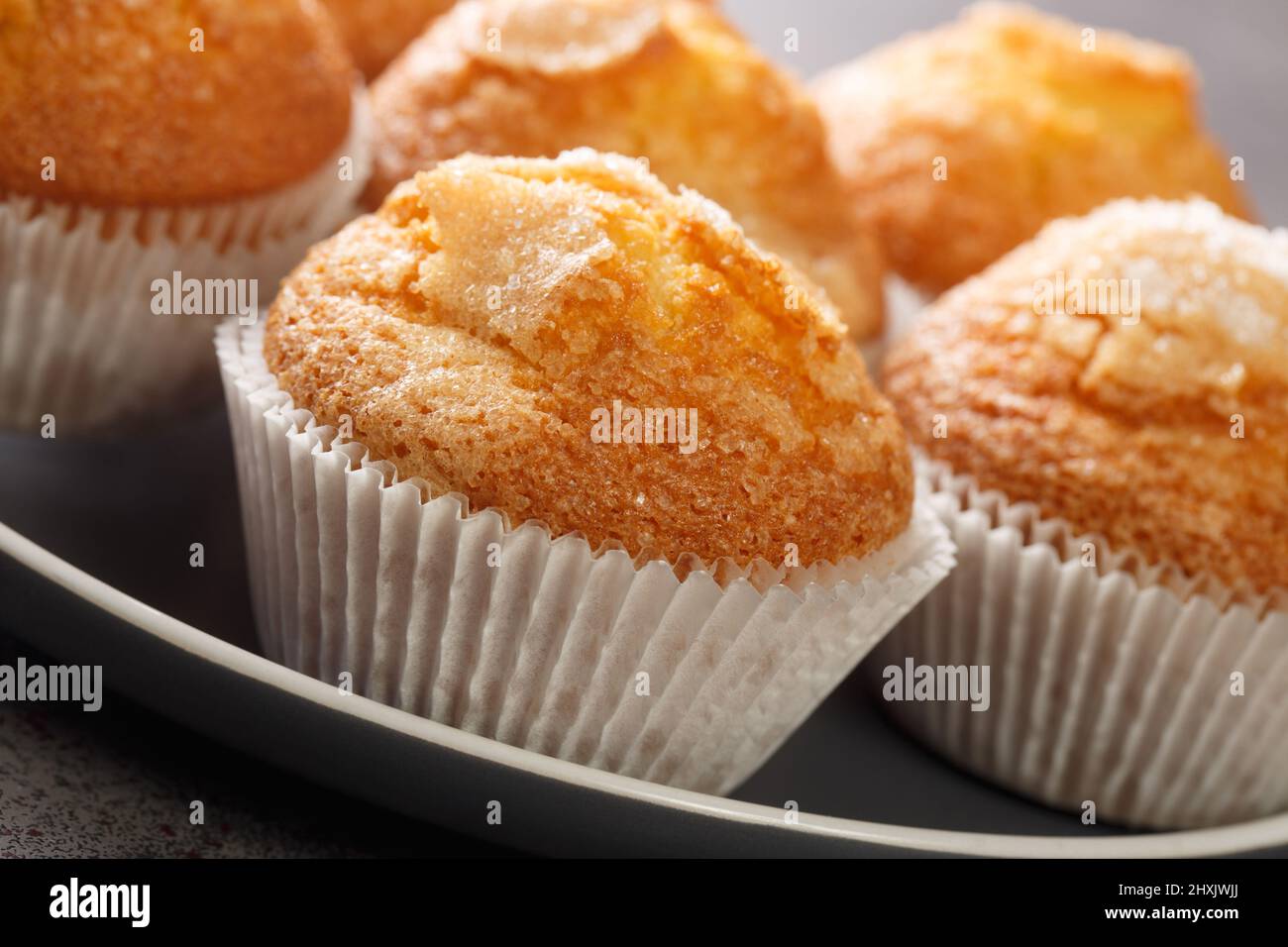 Primo piano di un mucchio di magdalenas i tipici muffin spagnoli pianura nel piatto sul tavolo. Orizzontale Foto Stock
