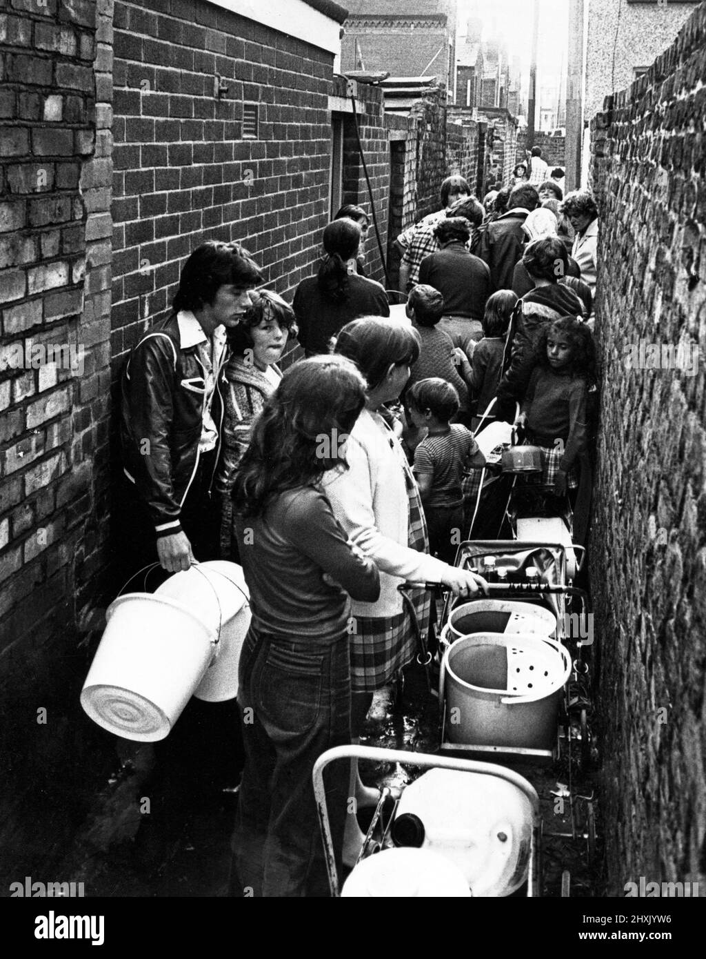 Le persone si accodano in un vicolo dietro David Street, la "Terra Santa", a Dingle, Liverpool, per l'acqua da un unico tubo. 25th luglio 1977. Foto Stock