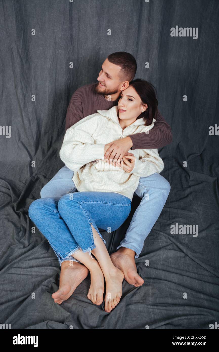 Una giovane coppia in amore trascorre del tempo in un abbraccio alla vigilia di Capodanno o San Valentino's Day.Dating in jeans casual. Sfondo in tessuto grigio. Foto Stock