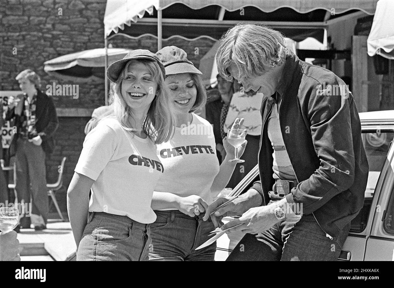 Motor Racing driver James Hunt firma il suo autografo per due delle sue stewardesses femminili ad un evento di incontro e saluto Chevette. Città e luogo sconosciuto Foto scattata circa il 1st agosto 1976 Foto Stock
