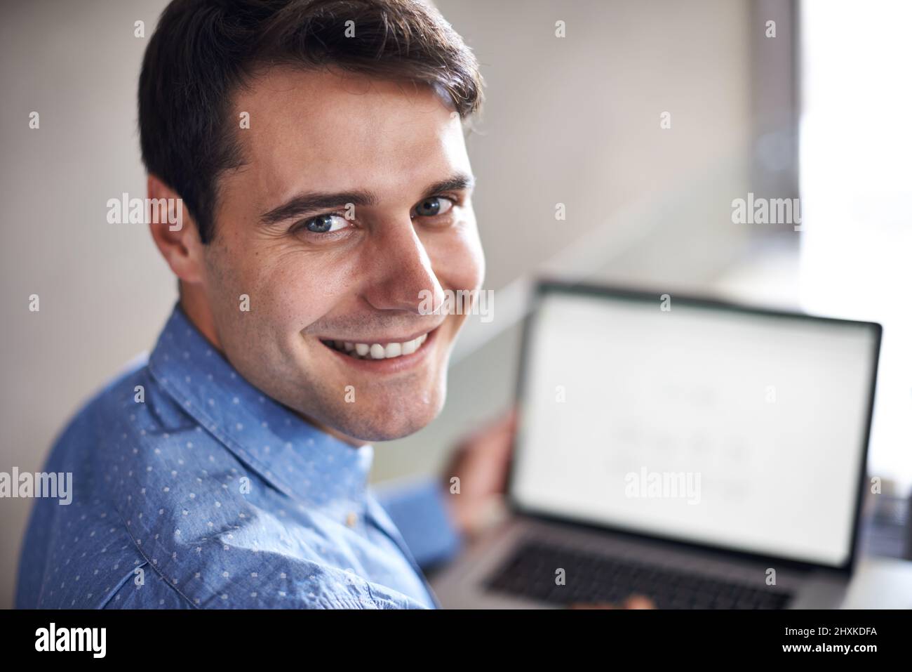 Il mio programma per oggi.... Ritratto di un giovane uomo d'affari che guarda sopra la spalla mentre si siede con il suo laptop. Foto Stock