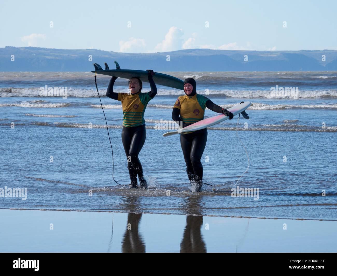 Due surfisti della scuola di surf che escono dal mare, Westward ho!, Devon, Regno Unito Foto Stock